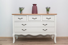 White Wooden Dresser With Three Vases And Flowers On White Wall Background. Chest Of Drawers Close Up.