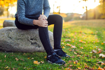 Woman having knee pain at the park. Medicine, health and people concept