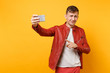 © ViDi Studio - Portrait vogue handsome young man in red leather jacket, t-shirt doing selfie on mobile phone isolated on bright trending yellow background. People sincere emotions lifestyle concept. Advertising area