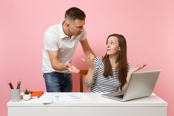 Two young angry business woman man colleagues sit work at white desk with contemporary laptop isolated on pastel pink background. Achievement career concept. Copy space advertising, youth co working.