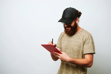 Happy bearded man wearing a black cap and working at tablet