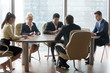 © fizkes - Diverse workers use gadgets at business meeting in modern office, employees browsing internet or check email holding devices, partners or colleagues busy with smartphone and laptop during negotiations