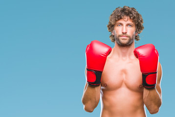 Poster - Handsome hispanic boxer man wearing boxing gloves over isolated background with serious expression on face. Simple and natural looking at the camera.