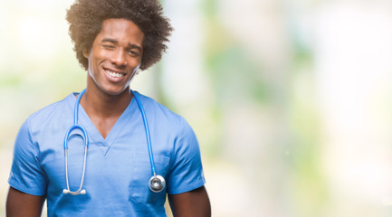 Poster - Afro american surgeon doctor man over isolated background winking looking at the camera with sexy expression, cheerful and happy face.