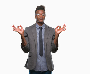 Canvas Print - Young african american business man over isolated background relax and smiling with eyes closed doing meditation gesture with fingers. Yoga concept.