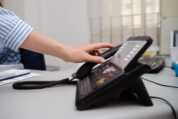 Close up of dialing a telephone device at office desk background, digital communication technology workplace. connection conference equipment group concept, happy professional telemarketer consulting