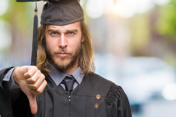 Canvas Print - Young handsome graduated man with long hair over isolated background looking unhappy and angry showing rejection and negative with thumbs down gesture. Bad expression.