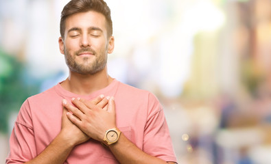 Canvas Print - Young handsome man over isolated background smiling with hands on chest with closed eyes and grateful gesture on face. Health concept.