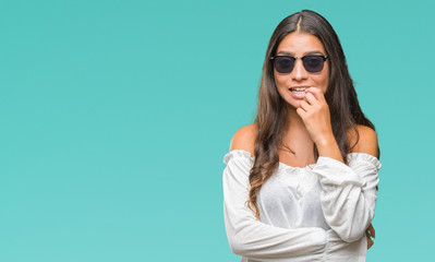 Poster - Young beautiful arab woman wearing sunglasses over isolated background looking stressed and nervous with hands on mouth biting nails. Anxiety problem.