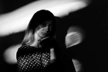 Portrait of a woman with shadows on face, wearing a polka dot blouse. Converted to black and white, grain added.