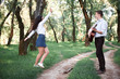 © soleg - young couple walking in the forest and playing guitar, summer nature, bright sunlight, shadows and green leaves, romantic feelings