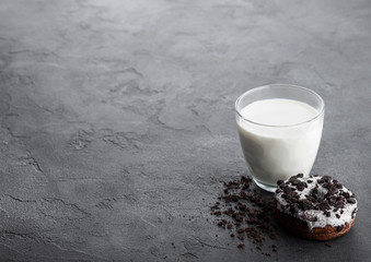 Glass of milk and doughnut with black cookies on black stone kitchen table background. Space for text.