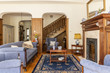 © Photographee.eu - A luxurious living room interior with antique sofa and coffee table in front of a fireplace in an English style mansion. Wooden staircase in the background. Real photo.