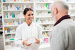 Medicine, pharmaceutics, health care and people concept - Happy female pharmacist giving medications to senior male customer