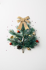 Wall Mural - top view of green pine branch decorated as festive christmas tree with bow on white background
