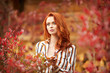 Outdoors portrait of beautiful woman with red hair and smoky eyes makeup
