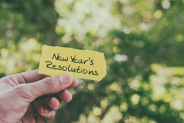 Wall Mural - Hands holding piece of paper with text - New Year's resolutions.