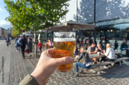 Beer in hand of visitor of street food market of Copenhagen, Denmark. Leisure in Scandinavia with drinks and food of popular city stores