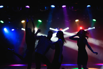 Nightlife and disco concept. Young people are dancing in club.