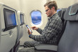 Mann studiert konzentriert seinen digitalen Lesestoff in einem Flugzeug