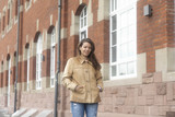 Fototapeta Na drzwi - Junge Frau gehend an einem alten Gebäude aus Backstein