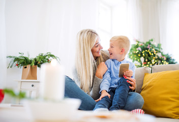 A mother and small boy with smartphone sitting on a sofa at home at Christmas time.