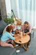 © LIGHTFIELD STUDIOS - high angle view of happy mature friends playing with wooden blocks at home