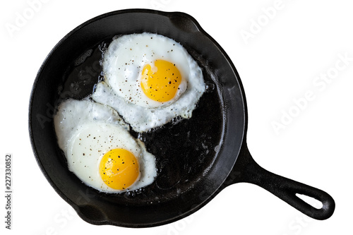Cuadros en Lienzo Two fried eggs in cast iron frying pan sprinkled with ground black pepper