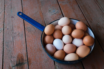  Chicken eggs from the farm. Eggs lie in a metal blue bowl on a wooden background