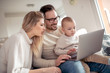 © ivanko80 - Smiling family with laptop sitting on sofa