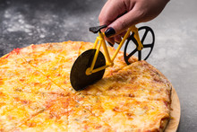 Female Hand Cutting Delicious Pizza With Cheese, Traditional Italian Cuisine. Knife If Form Of Bike