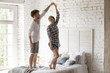 © fizkes - Young couple in love standing in bedroom having fun at home. Woman and man holding hands dancing enjoying date spending time together. Just a married romantic relations or relocate at new home concept
