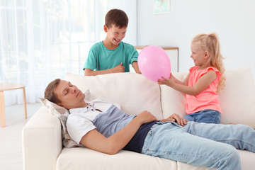 Sticker - Mischievous kids ready to pop balloon over their sleeping father at home. April fool's day prank