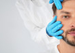 Leinwandbild Motiv Doctor examining mature man face before cosmetic surgery on white background, closeup