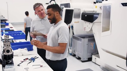 Wall Mural - engineer and male apprentice measuring components in hi tech engineering plant