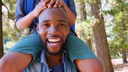 Wall Mural - Portrait Of Father Walking In Woods Carrying Son On Shoulders 