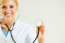 Young Female Doctor Pointing Stethoscope At Blank Space. Selective Focus At Doctors Hand. Medical Healthcare Concept.
