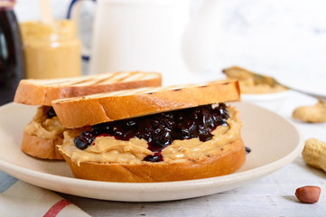 Wall Mural - Toast with peanut butter and berry jam on a plate, tea. Nutritious breakfast.