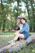 © soleg - young couple sitting on a log in the forest and playing guitar, summer nature, romantic feelings