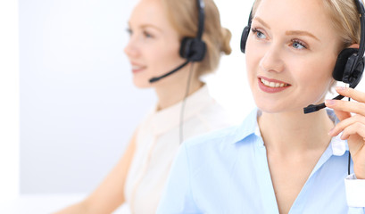 Bright  call center office. Two blonde women in a headset