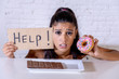 Sad woman on diet holding a sign help resisting temptation to eat chocolate and donuts
