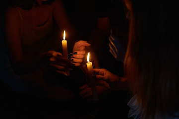 hands holding a burning candle in dark