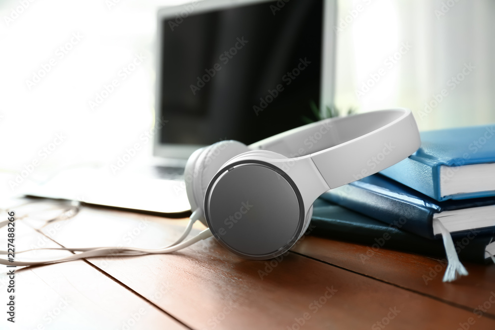 Modern headphones and notebooks on wooden table