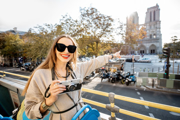 Young woman enjoying a beautiful view on the Notre-Dame cathedral during a bus tour in Paris, France