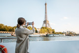 Fototapeta Paryż - Young woman enjoying beautiful landscape view on the riverside with Eiffel tower from the boat during the sunset in Paris
