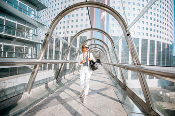 Business woman walking with bag and phone on the modern covered bridge at the business center in Paris