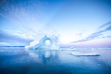 Wall Mural - photogenic and intricate iceberg with a hole under an interesting and colorful sky during sunrise wi
