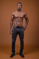 Handsome muscular African man shirtless against brown background