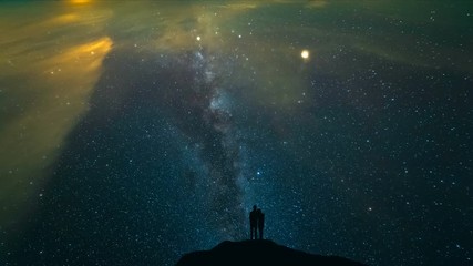 Wall Mural - The couple standing on a night mountain with a starry sky background. time lapse