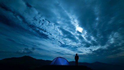 Wall Mural - The male near camping tent standing on a night mountain. time lapse
